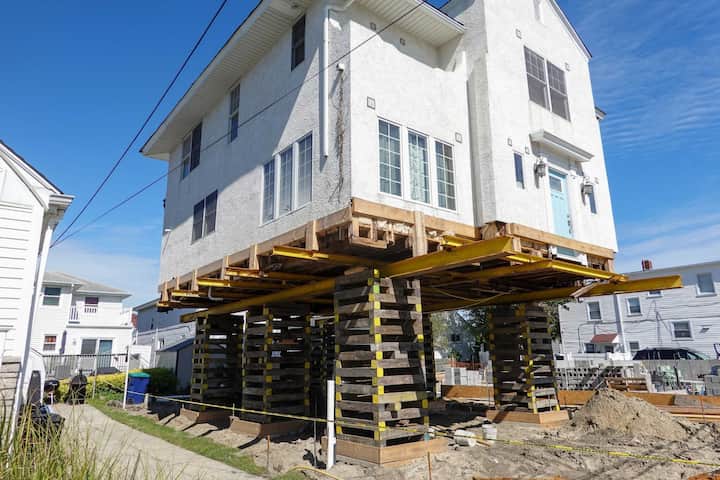 A team of professionals using specialized equipment to raise a house in Green Bay, preparing it for elevation and renovation